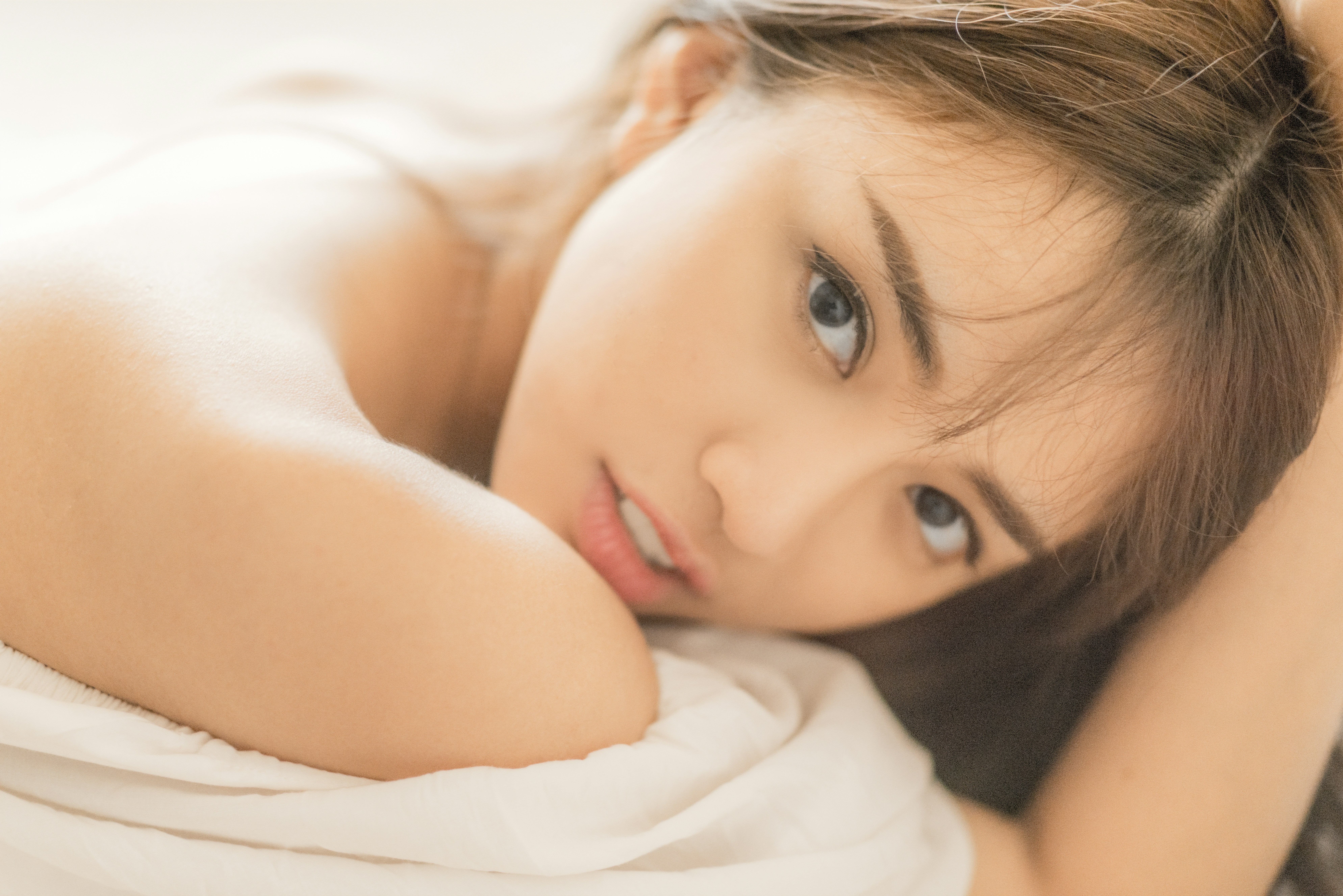 A woman lying down and looking at the camera.